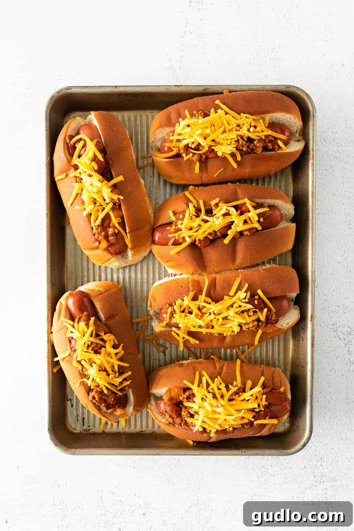 A pan filled with assembled chili cheese dogs, ready for baking.