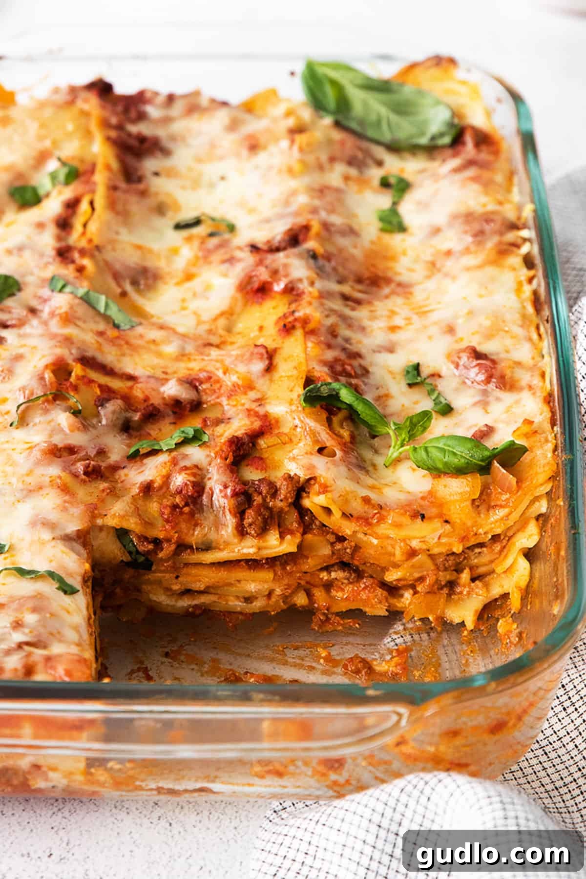 The Ultimate Meat Lasagna 6 A large, golden-brown meat lasagna in a glass baking dish, fresh out of the oven and ready to be served.