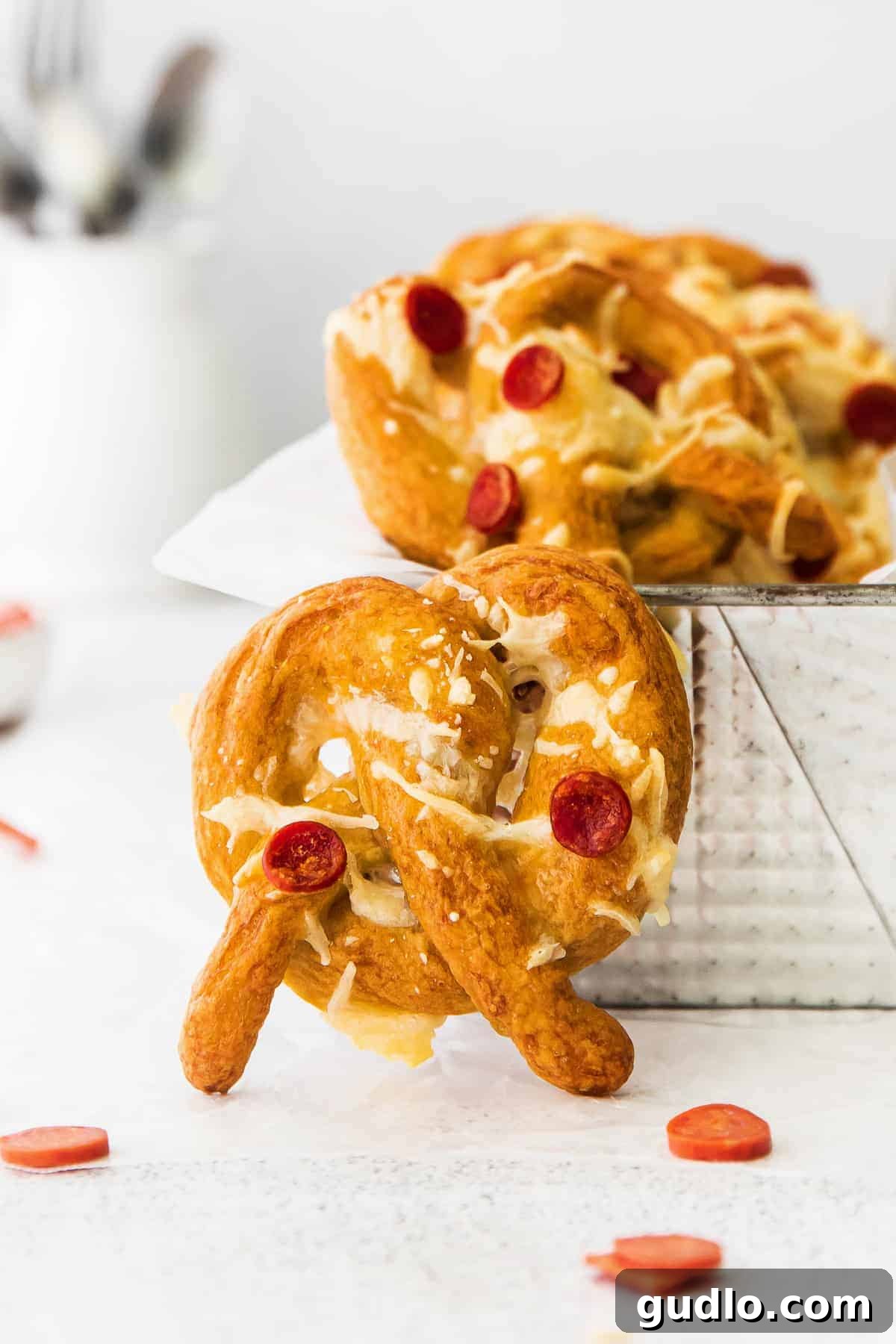 These pizza soft pretzels are such a fun snack or appetizer to make that the whole family will enjoy. Top them with your favorite pizza toppings! A hand holding a perfectly golden-brown pizza soft pretzel, showcasing the melted cheese and pepperoni toppings up close.