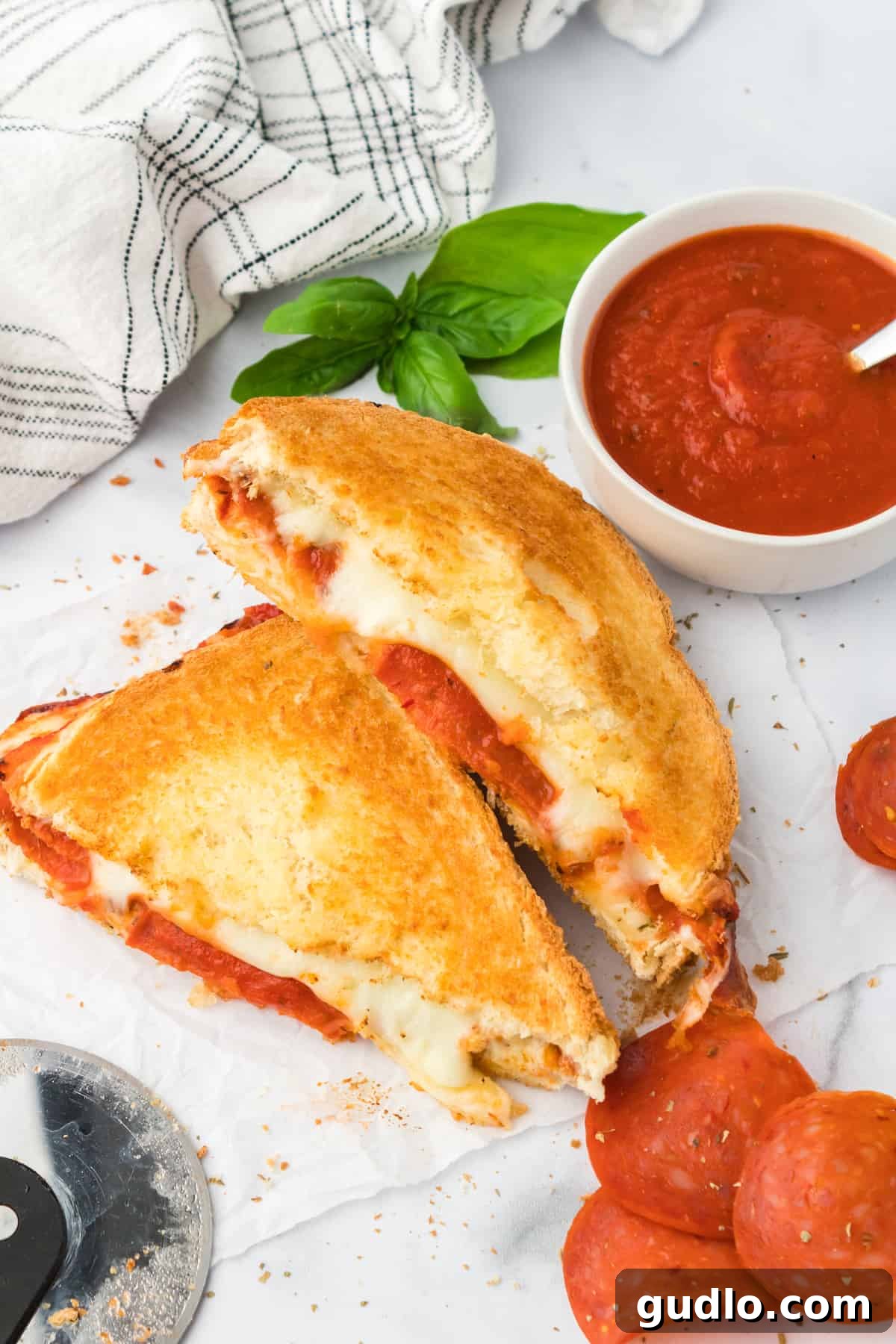 Delicious Air Fryer Pizza Grilled Cheese, sliced to show its cheesy, pizza-filled interior. Sliced grilled cheese on counter, revealing pizza filling.