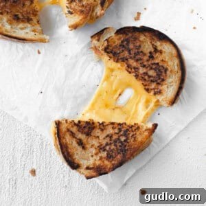 Classic Grilled Cheese, perfectly golden and melted. Crispy grilled cheese on parchment paper, ready to be served.