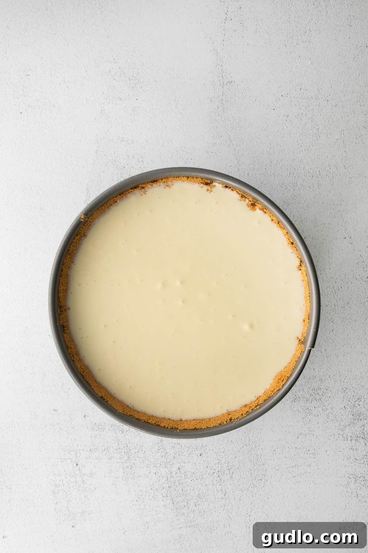A classic cheesecake baking inside a springform pan, showing its perfect golden edges.