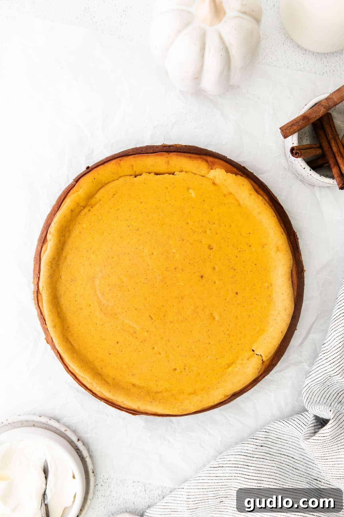 Chai Pumpkin Cheesecake Ready to Serve A whole Chai Pumpkin Cheesecake, perfectly baked and chilled, standing tall in a springform pan, ready to be sliced and served, showcasing its smooth top and inviting color.