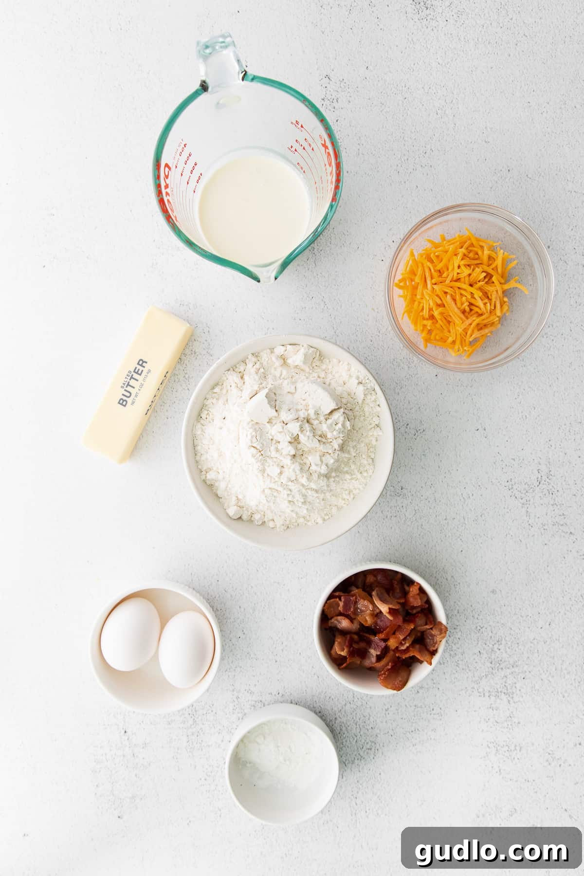 All the fresh ingredients for bacon and cheddar scones laid out on a kitchen countertop, ready for preparation.