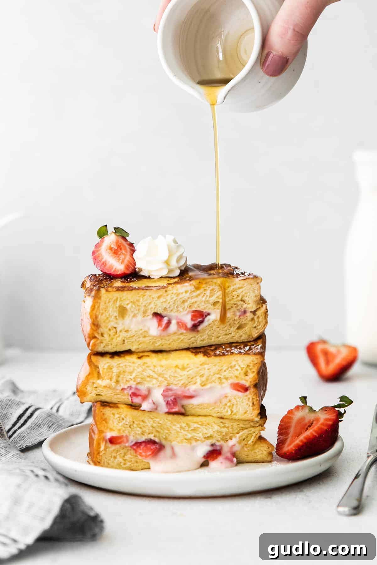 Decadent Strawberries and Cream Stuffed French Toast drizzled with maple syrup.