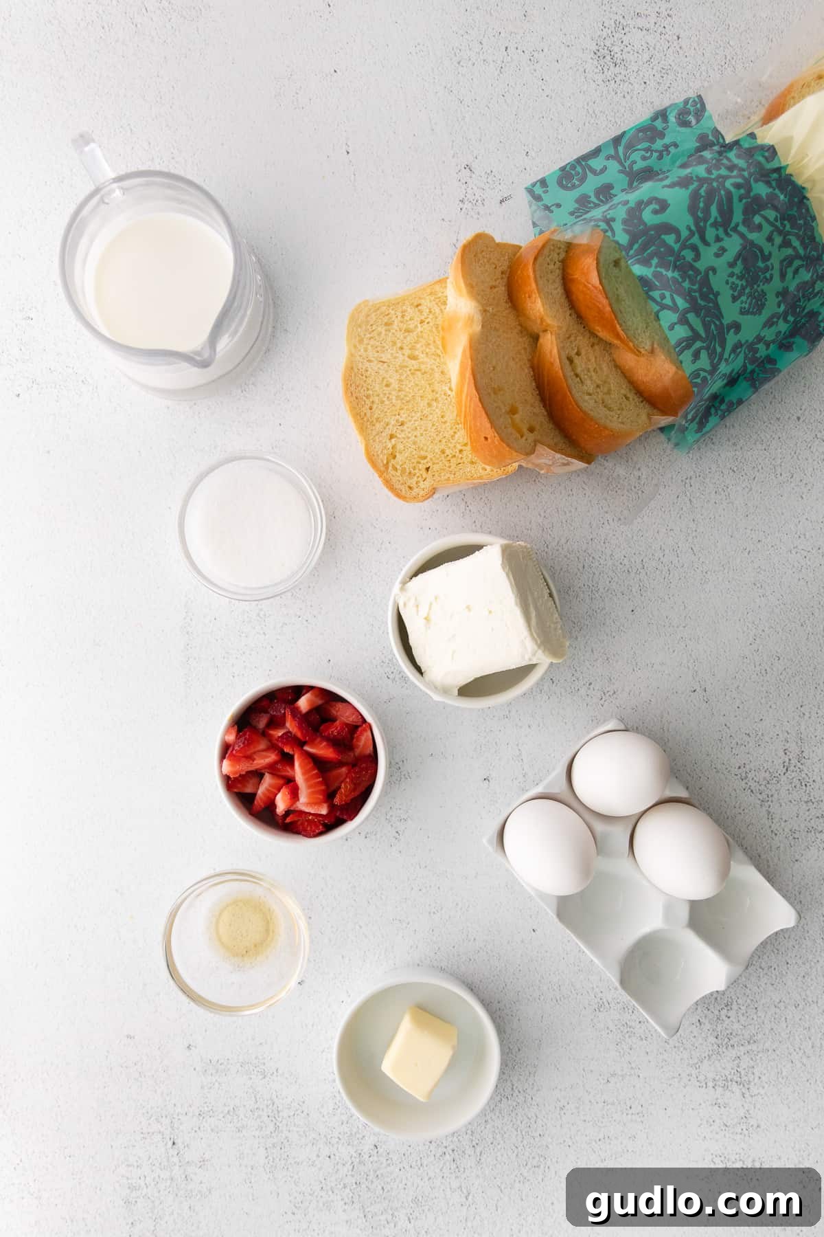 Ingredients for Strawberries and Cream Stuffed French Toast laid out on a kitchen counter.
