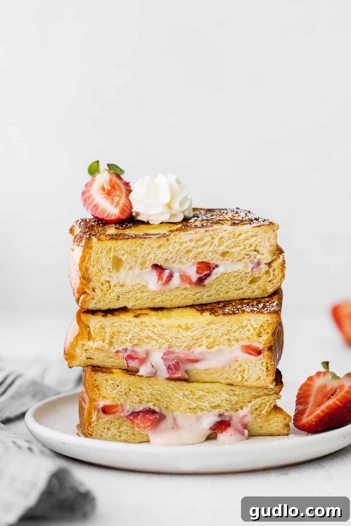 Three slices of Strawberries and Cream Stuffed French Toast stacked and ready to serve.