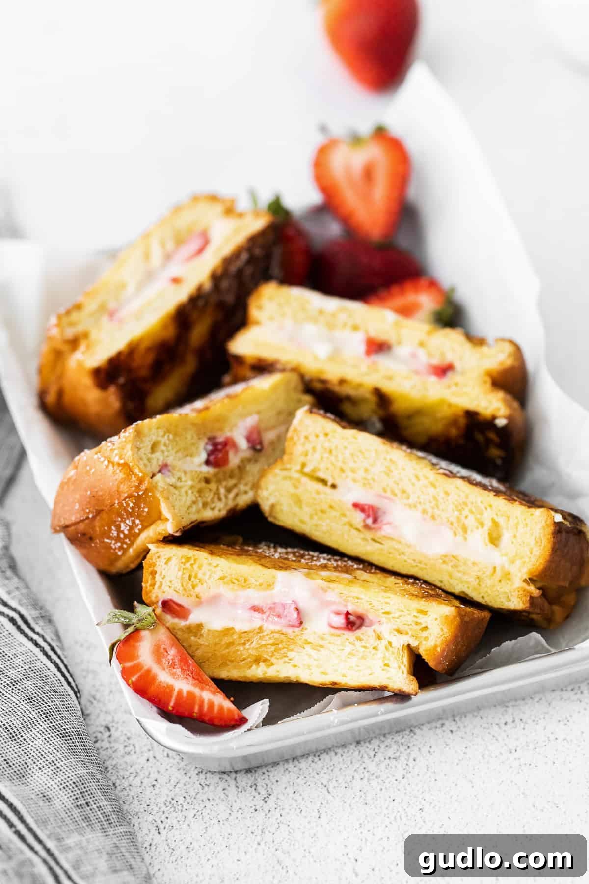 Beautifully arranged Strawberries and Cream French Toast in a serving tray, garnished with fresh berries.