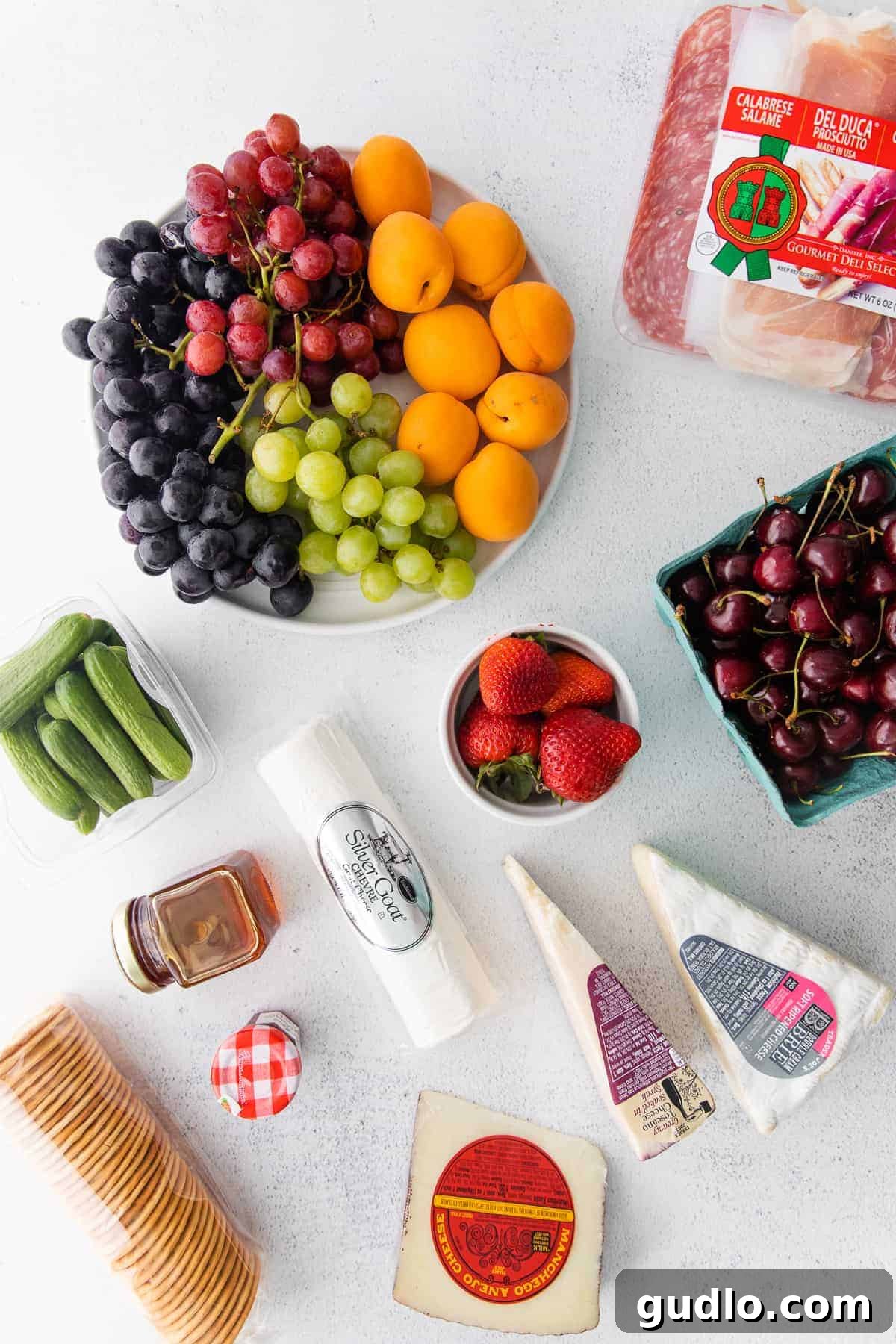 Fresh Produce for Your Gourmet Cheese Platter A plate featuring a colorful assortment of fresh fruits and vegetables, including grapes, strawberries, and cucumber slices, ready for a cheese board.