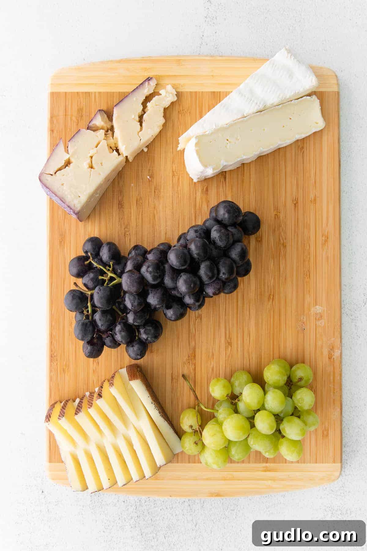 Juicy Grapes: An Essential Cheese Board Element Close-up of a bunch of ripe red grapes, glistening on a rustic cutting board, highlighting their vibrant color and plump texture.