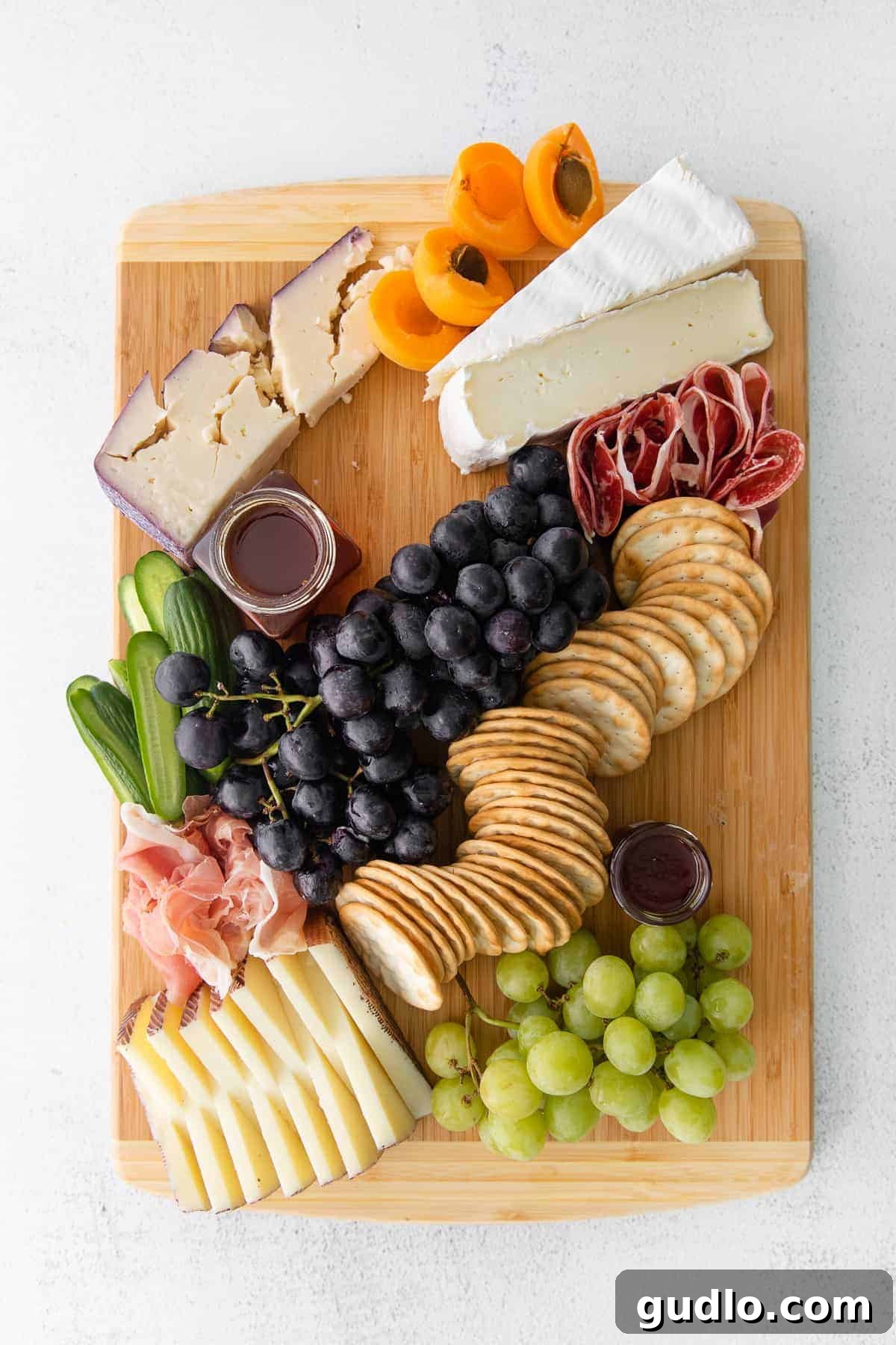 Gourmet Cheese Board with Savory Meats and Fresh Fruits A close-up of a beautifully assembled cheese board featuring grapes, various cheeses, and slices of cured meat, inviting guests to enjoy.