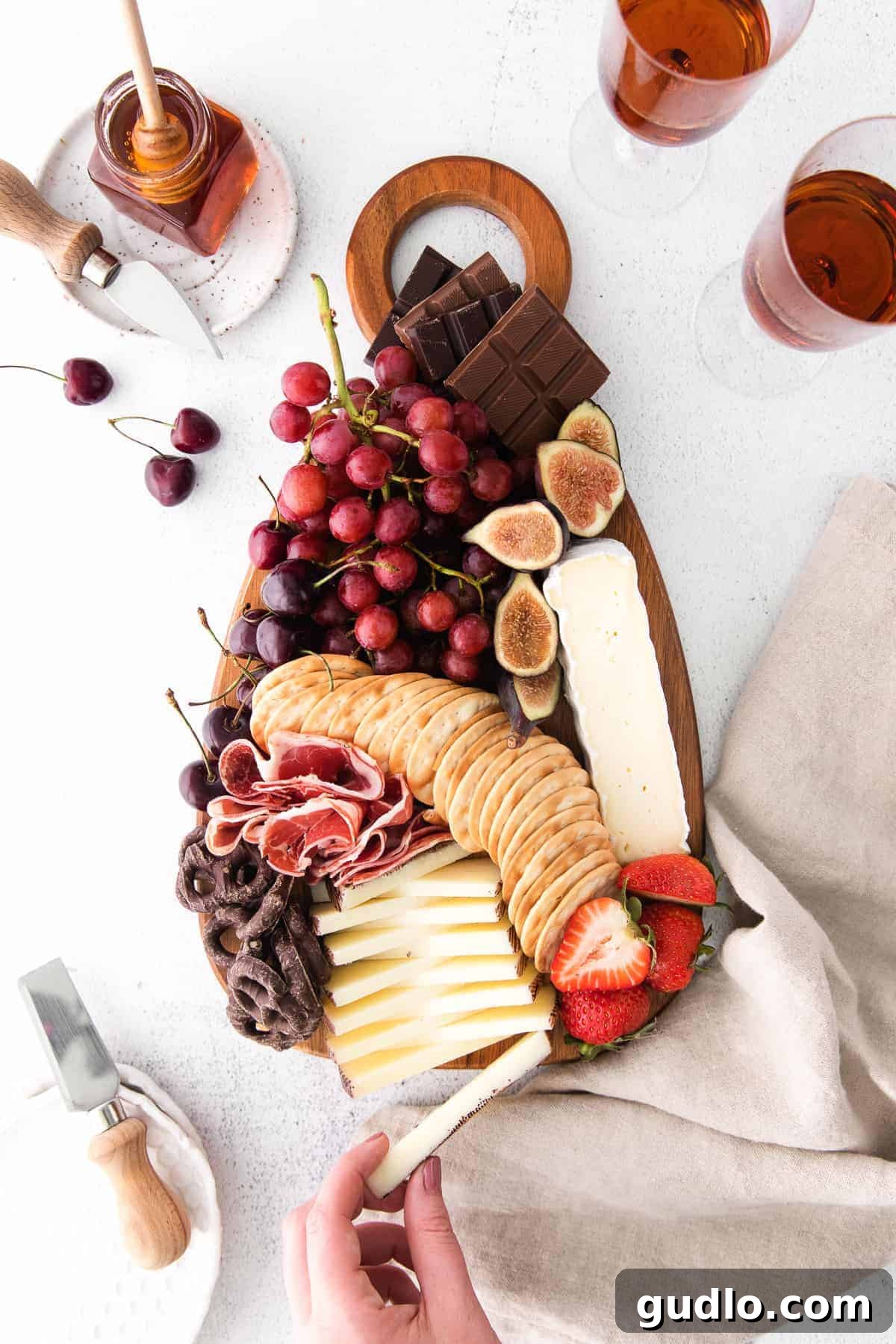 An elegantly arranged chocolate and cheese board featuring crackers, fresh grapes, various cheeses, and chocolate bars.