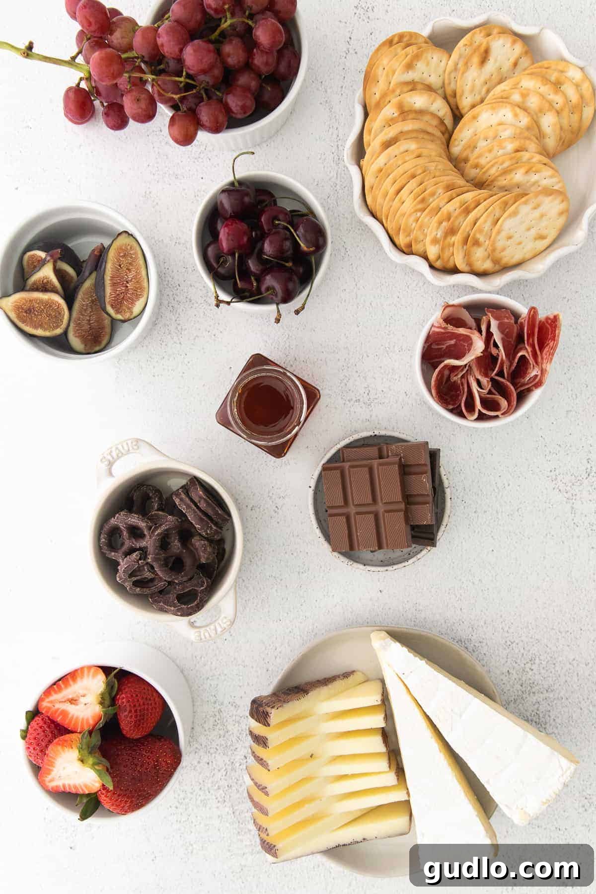 Assortment of ingredients for a chocolate and cheese board, neatly arranged in small bowls, ready for assembly.
