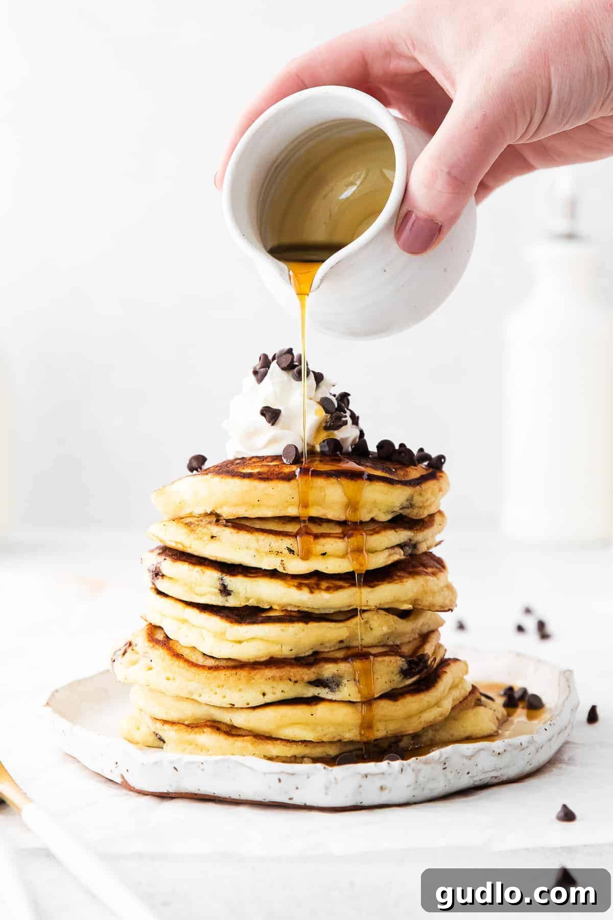 Indulgent Chocolate Chip Ricotta Pancakes with Maple Syrup Golden chocolate chip ricotta pancakes drizzled generously with maple syrup, ready to be enjoyed.