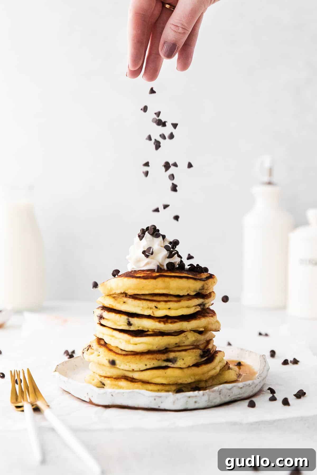 Adding Chocolate Chips to Fluffy Pancakes Someone sprinkling a handful of chocolate chips onto freshly cooked golden brown ricotta pancakes on a griddle.