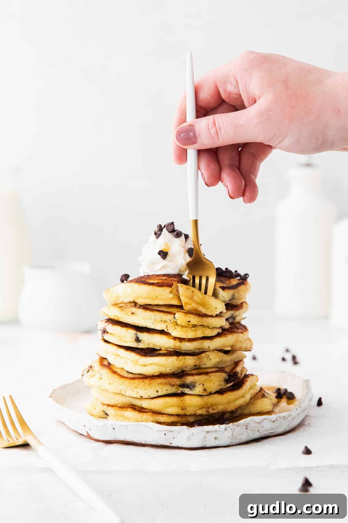 A Mouthwatering Bite of Ricotta Pancake A fork taking a bite out of a stack of fluffy chocolate chip ricotta pancakes, revealing their tender interior.