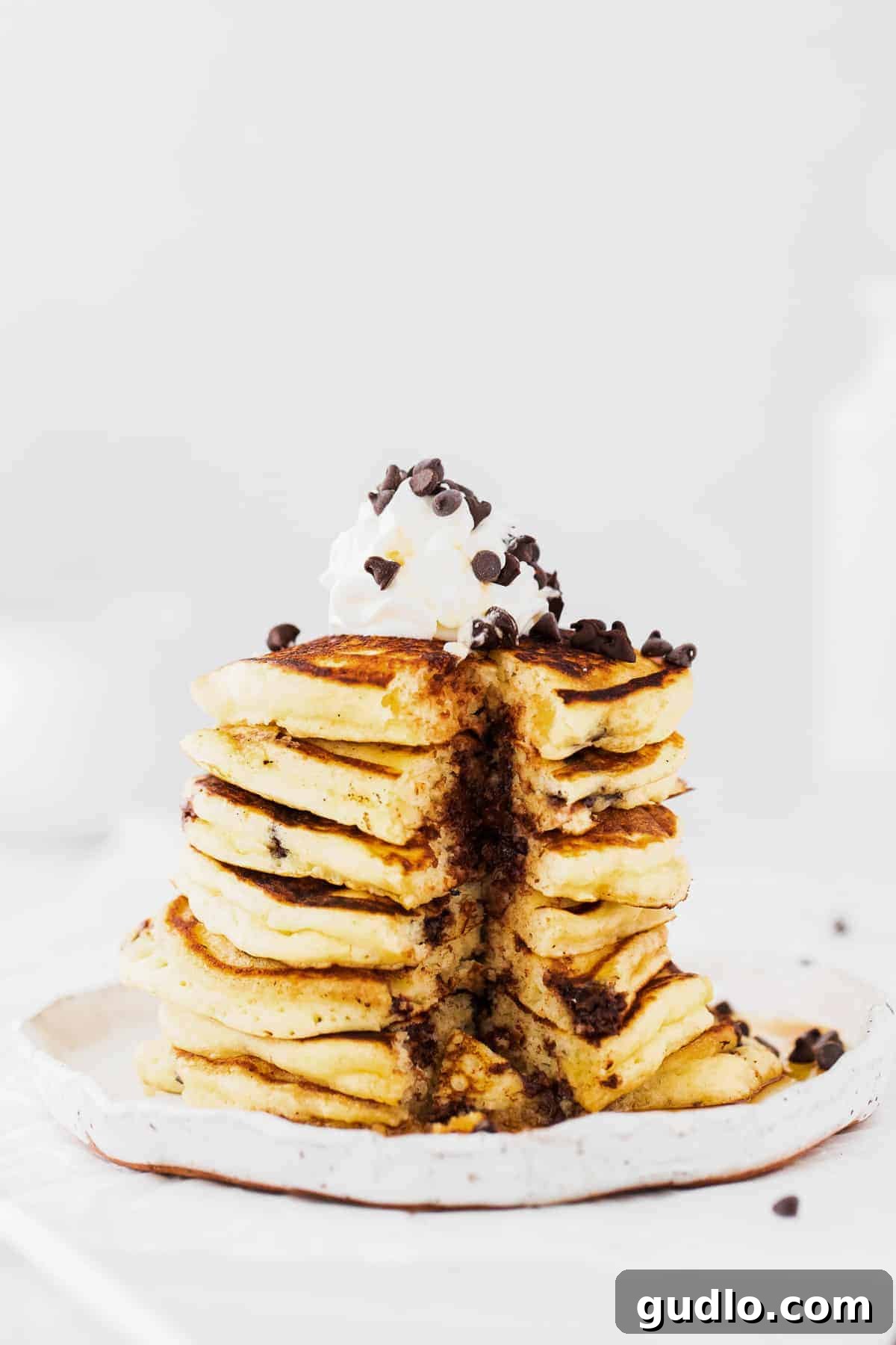 A Delightful Breakfast Experience with Ricotta Pancakes A beautifully arranged stack of chocolate chip ricotta pancakes on a white plate, garnished with fresh berries and a drizzle of syrup.