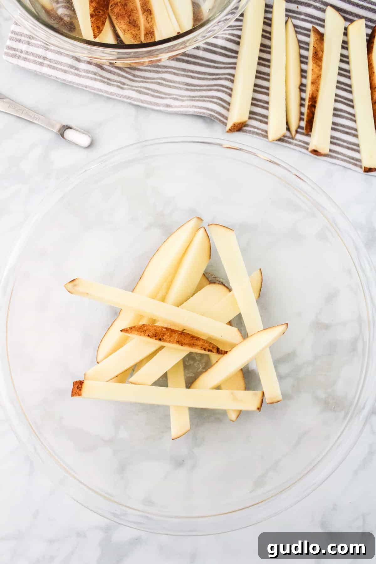 Freshly sliced russet potatoes soaking in a bowl of cold water.