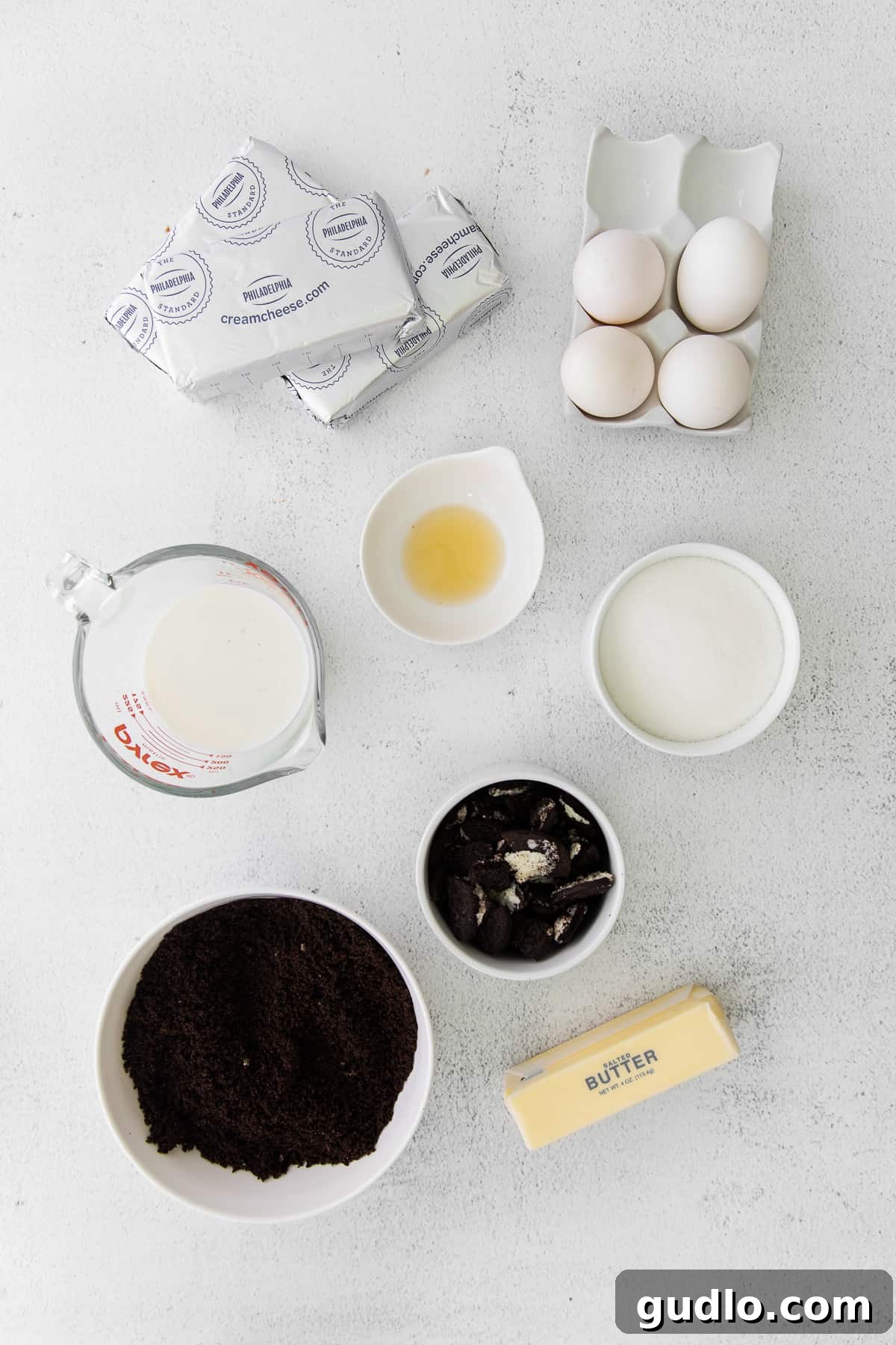 All the essential ingredients for Oreo cheesecake, including cream cheese, Oreos, and butter, laid out on a kitchen counter, ready for preparation.