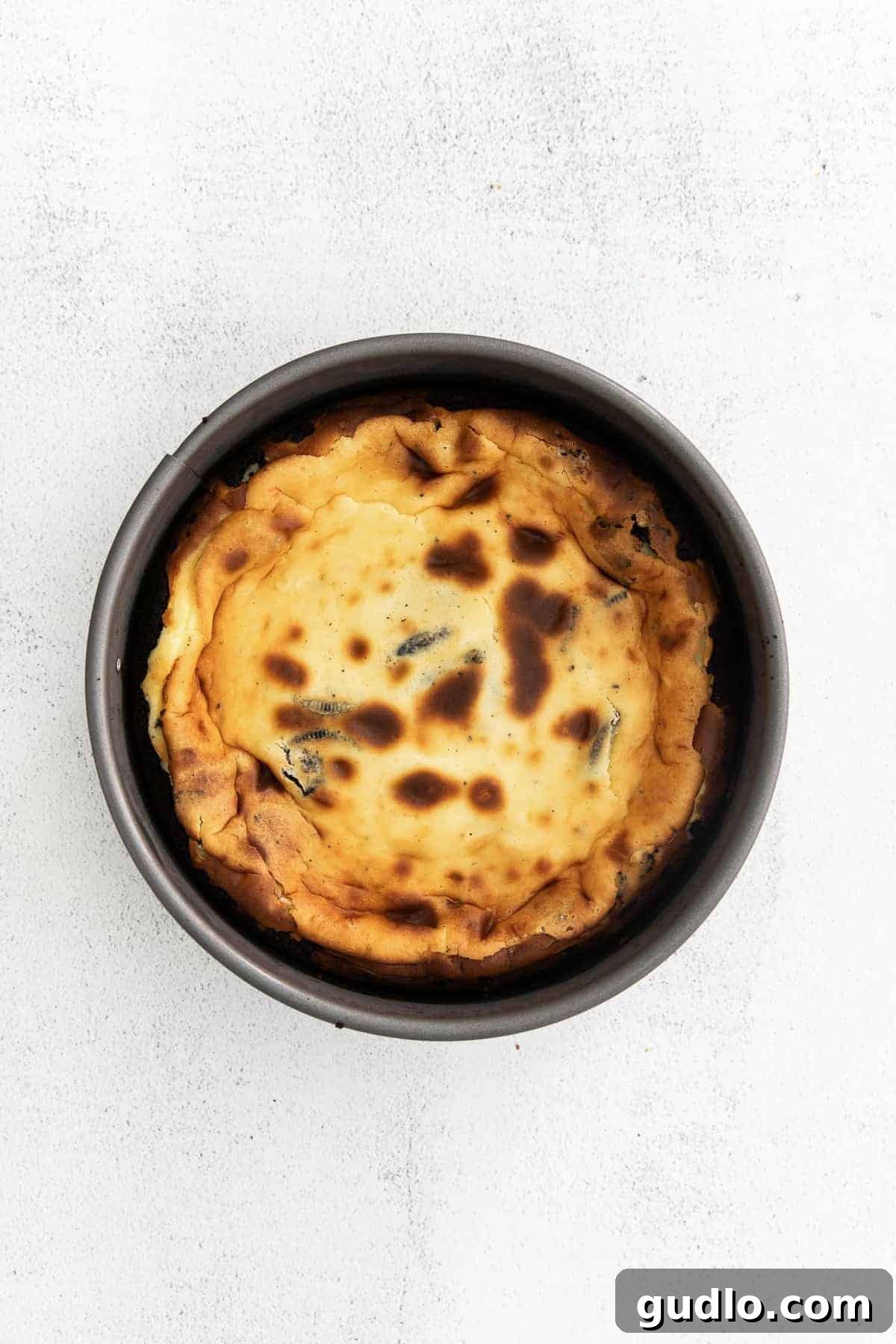 A freshly baked Oreo cheesecake in a springform pan, showing its golden-brown edges and slightly puffed center.