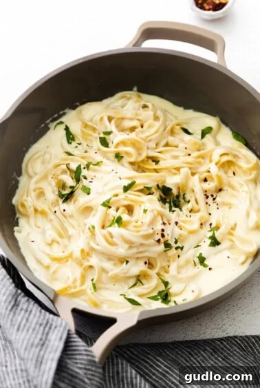 Creamy Alfredo sauce ready in a pan, awaiting pasta to be tossed in.