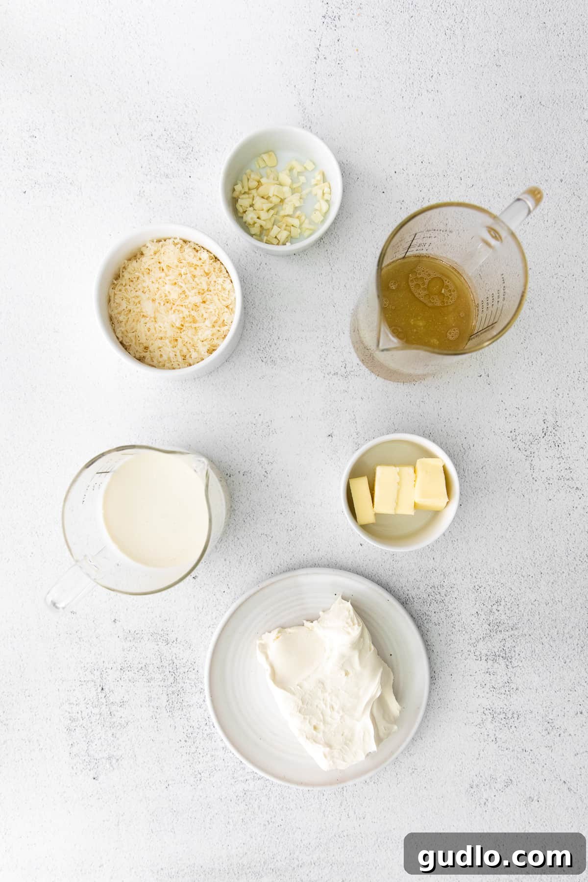 Gather these simple yet powerful ingredients for a quick and incredibly creamy Alfredo sauce with a cream cheese twist. A selection of fresh ingredients neatly arranged in small bowls, showcasing the quality components required for making cream cheese Alfredo sauce.