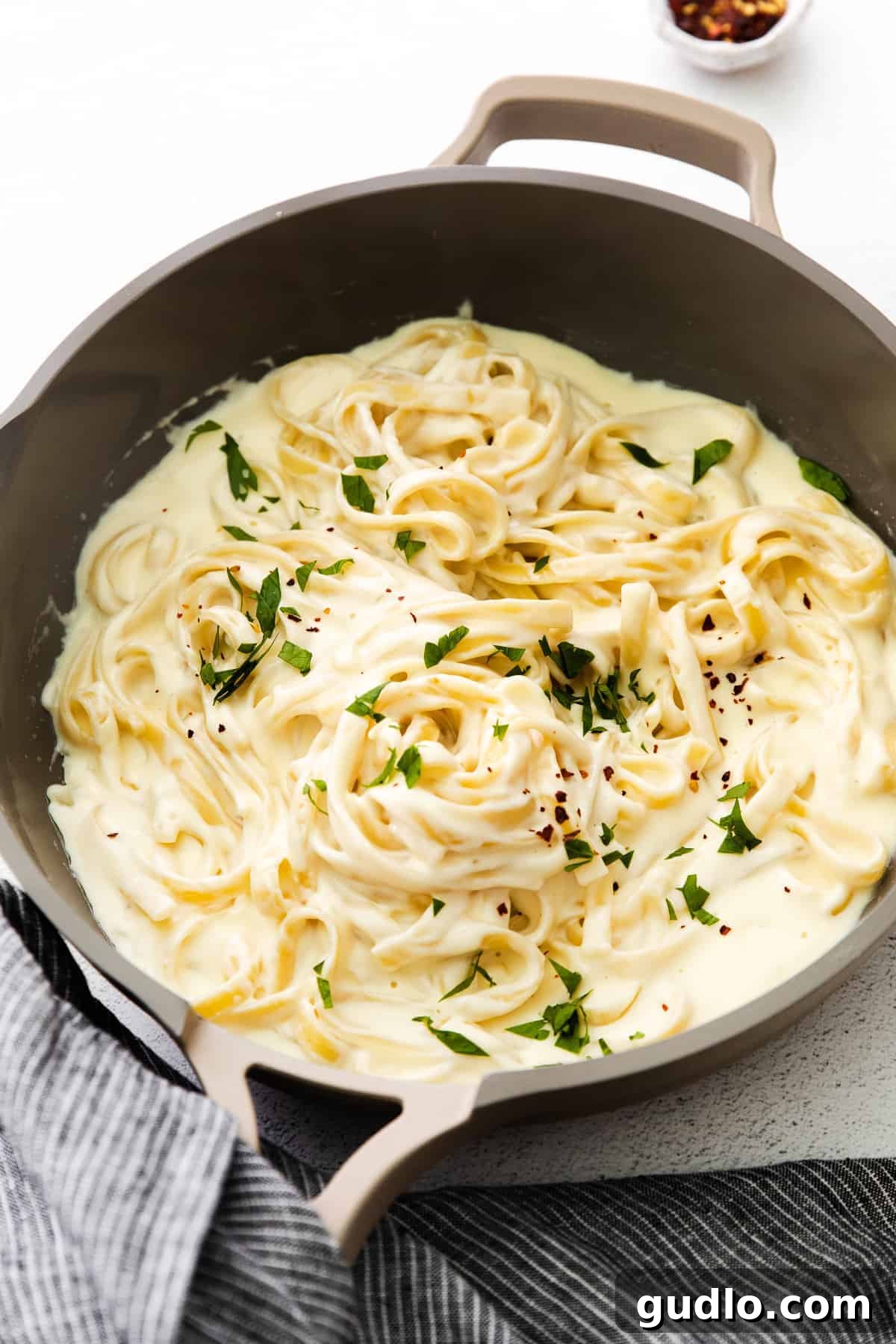 Our Alfredo Sauce with Cream Cheese is made oh so creamy and flavorful with 6 easy ingredients. Pair with your favorite pasta, and enjoy! Fettuccine noodles generously coated in cream cheese Alfredo sauce, garnished with fresh parsley and served invitingly in a skillet.