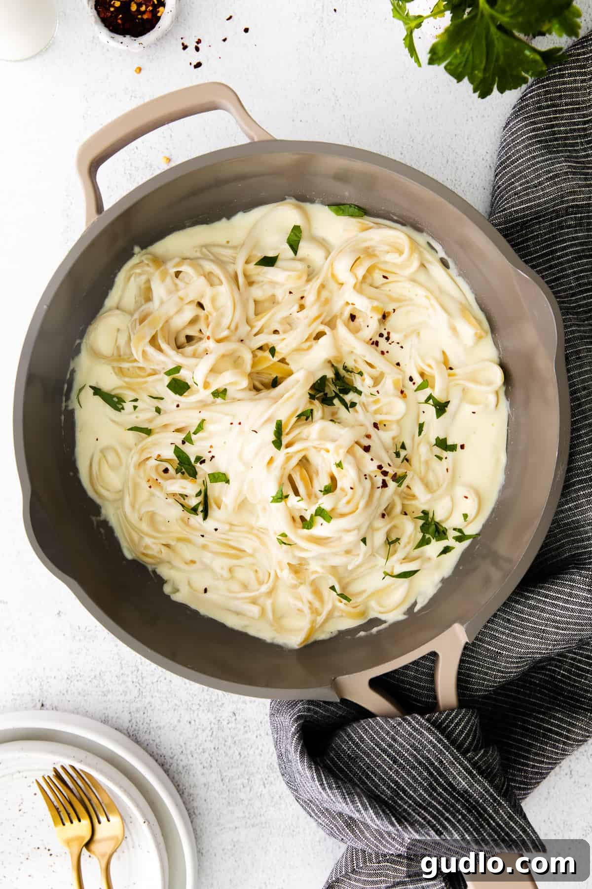 Our Alfredo Sauce with Cream Cheese is made oh so creamy and flavorful with 6 easy ingredients. Pair with your favorite pasta, and enjoy! A large skillet filled with perfectly cooked fettuccine noodles awaiting a generous coating of our luscious Alfredo sauce, creating a mouthwatering scene.