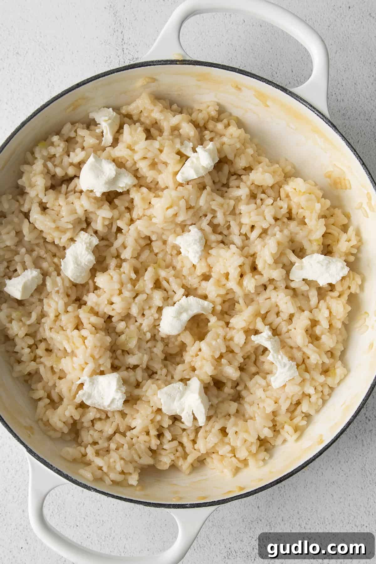 The perfect creamy consistency of homemade risotto, ready to be enriched with goat cheese. Creamy, perfectly cooked risotto simmering gently in a large pot, ready for the final touches.