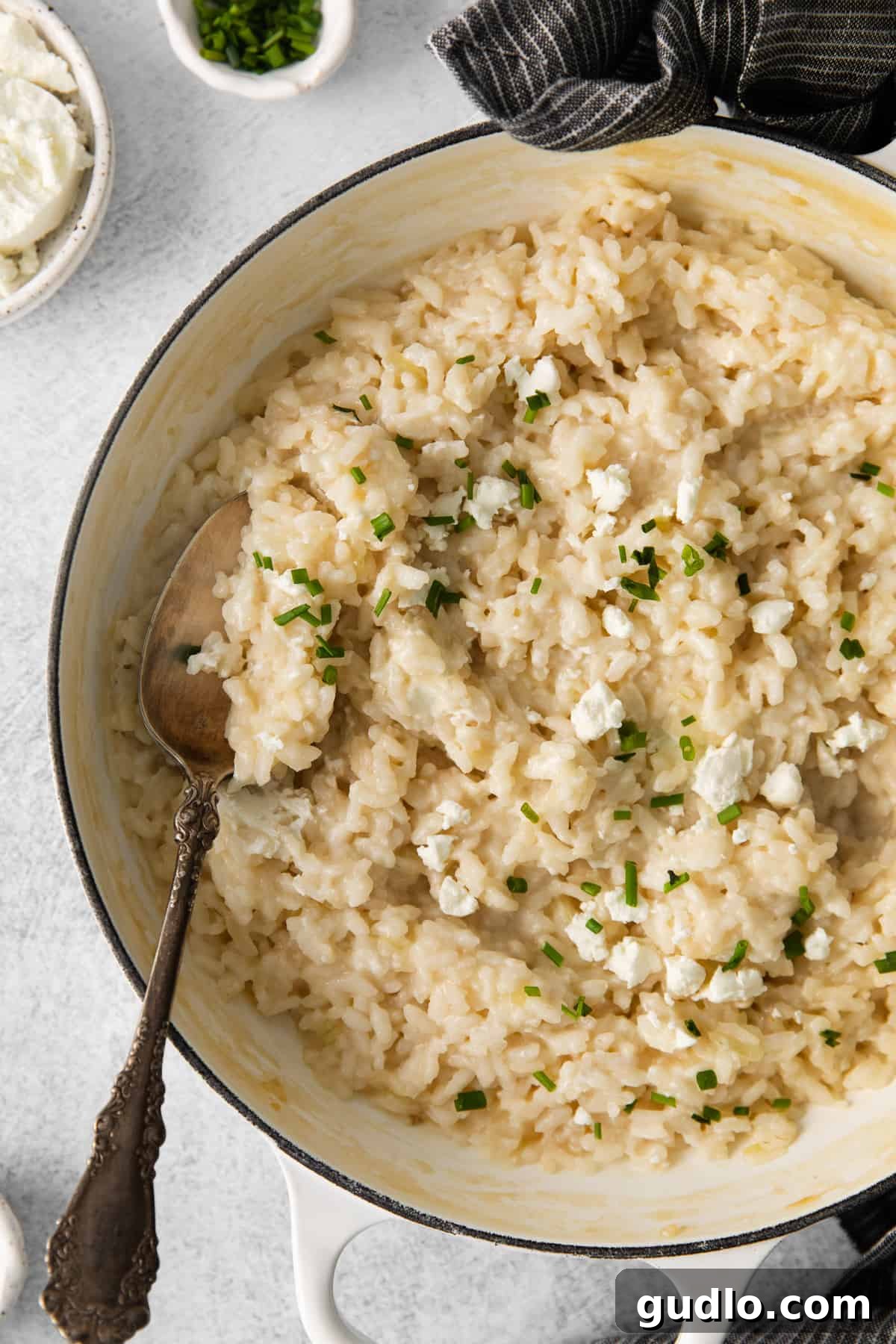 A steaming pot of goat cheese risotto, garnished and ready to be enjoyed. A large pot of freshly prepared goat cheese risotto, topped with crumbled goat cheese and fresh sage.
