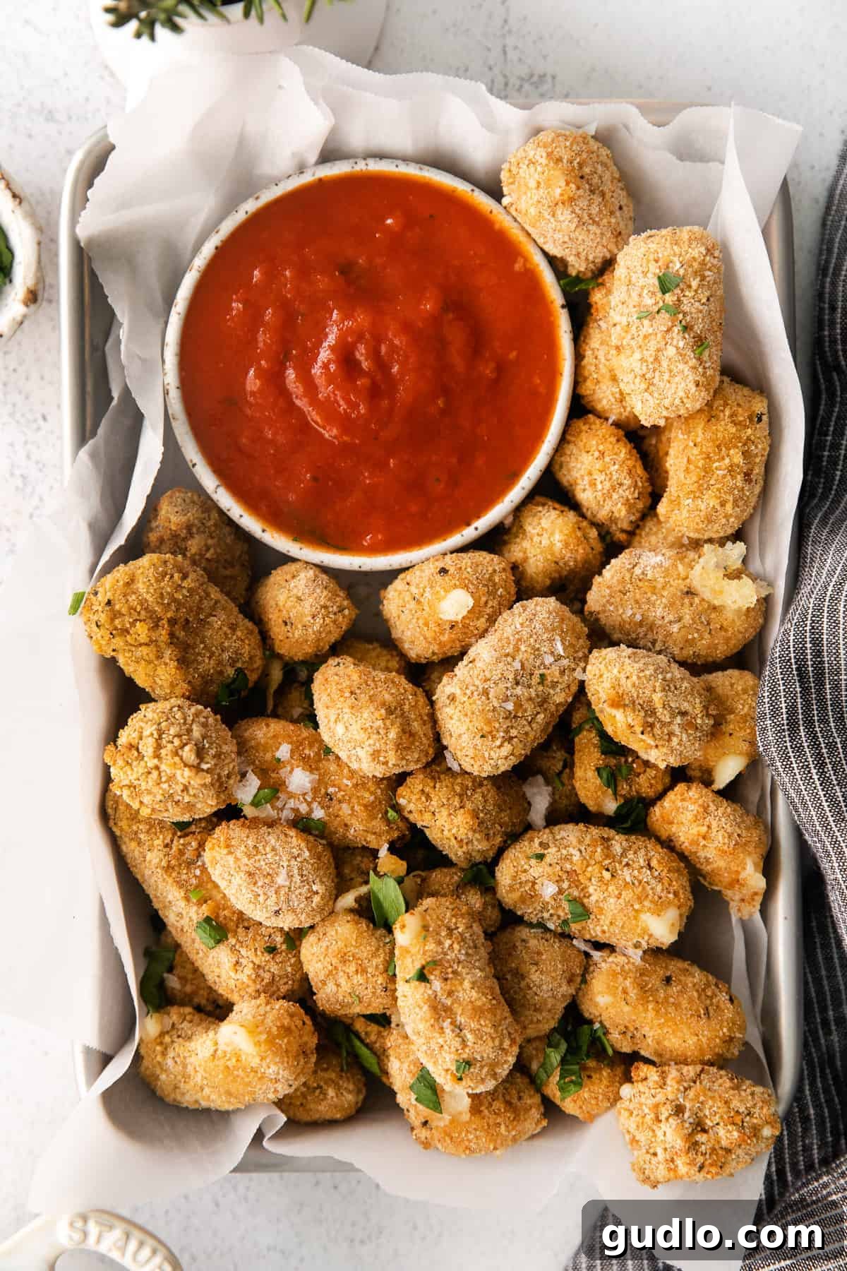 These air fryer cheese curds are made perfectly crispy in the air fryer in no time at all! Serve these as an appetizer or game day snack. air fryer cheese curds in a basket with a bowl of marinara sauce