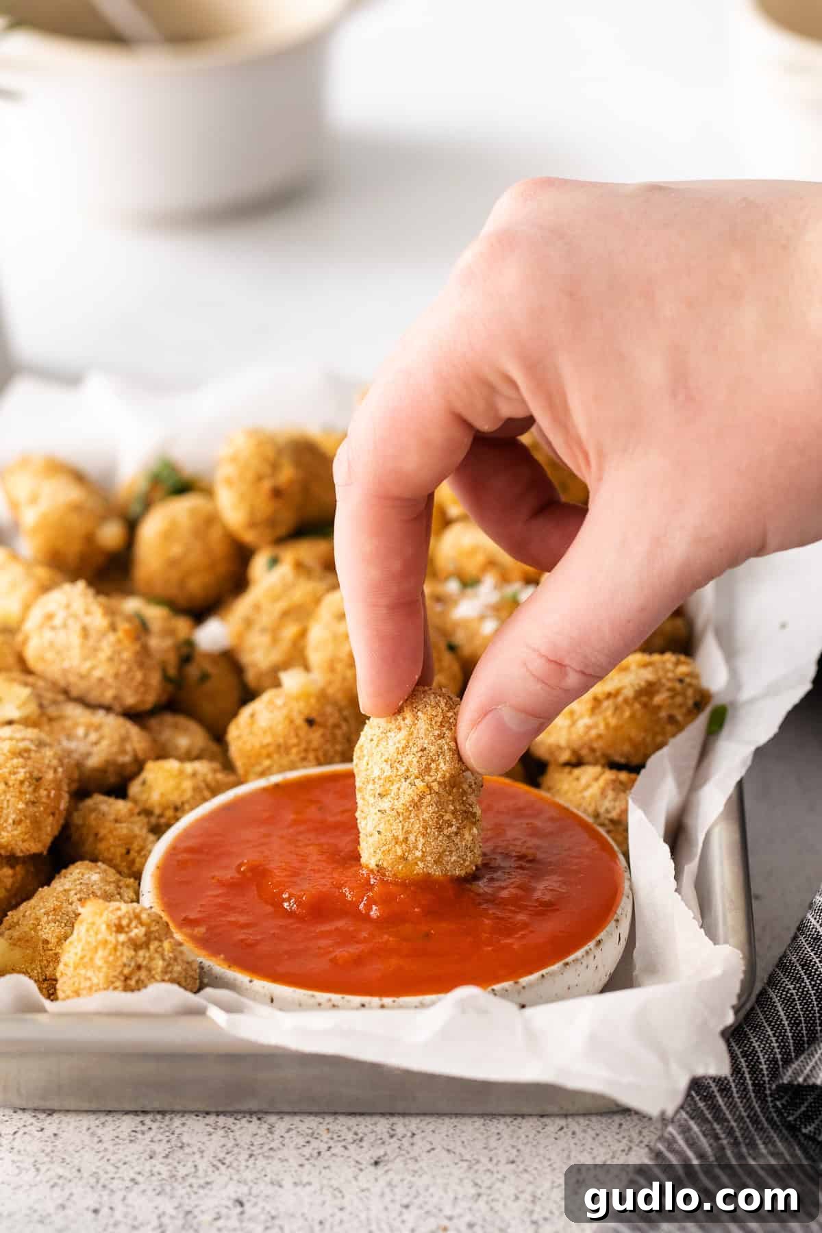 These air fryer cheese curds are made perfectly crispy in the air fryer in no time at all! Serve these as an appetizer or game day snack. cheese curd being dipped into marinara sauce