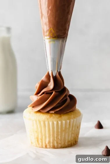 Velvety Chocolate Cream Cheese Delight 10 A beautifully frosted cupcake with a swirl of chocolate cream cheese frosting, garnished with sprinkles. A chocolate frosting being poured onto a cupcake.