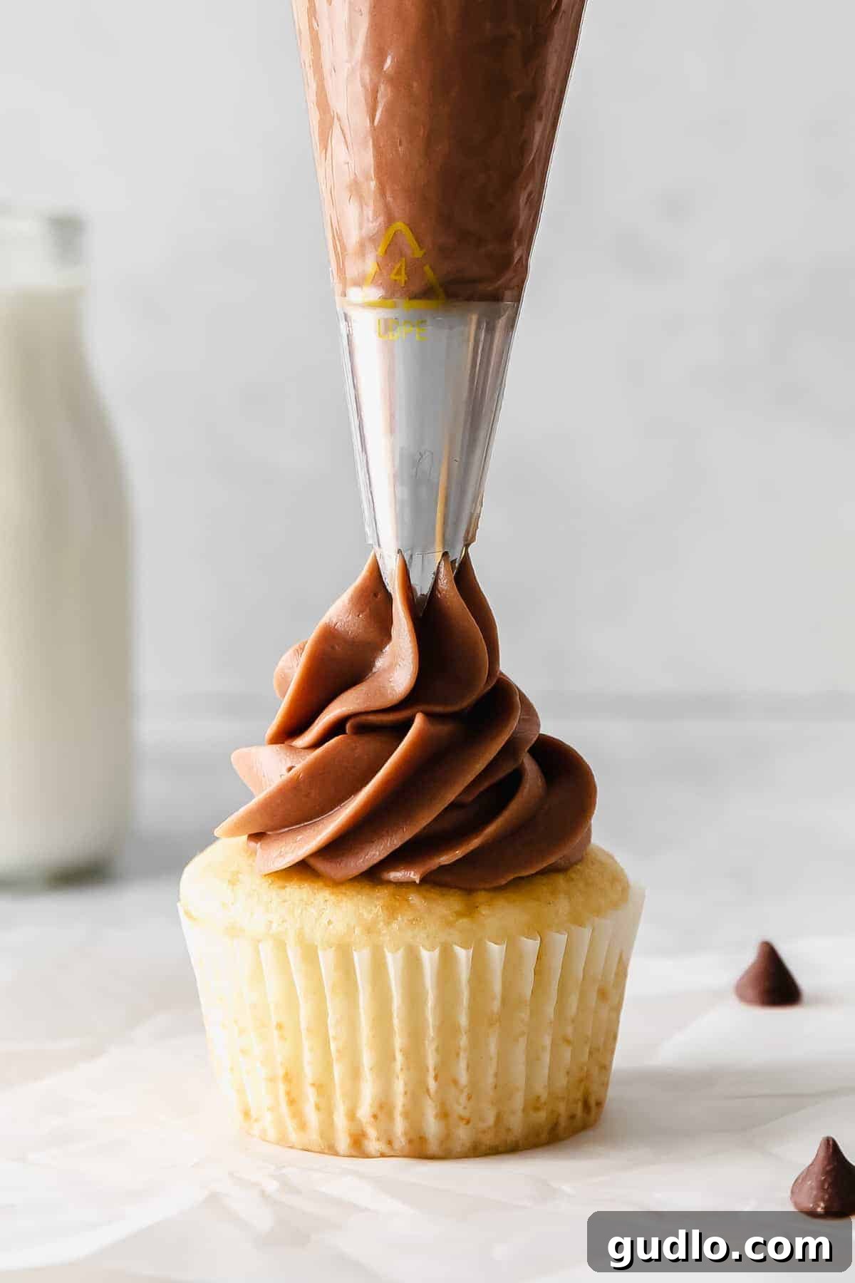 Velvety Chocolate Cream Cheese Delight 5 A cupcake being expertly frosted with a swirl of rich chocolate cream cheese frosting using a piping bag. Use this chocolate cream cheese frosting to frost your favorite cupcakes.