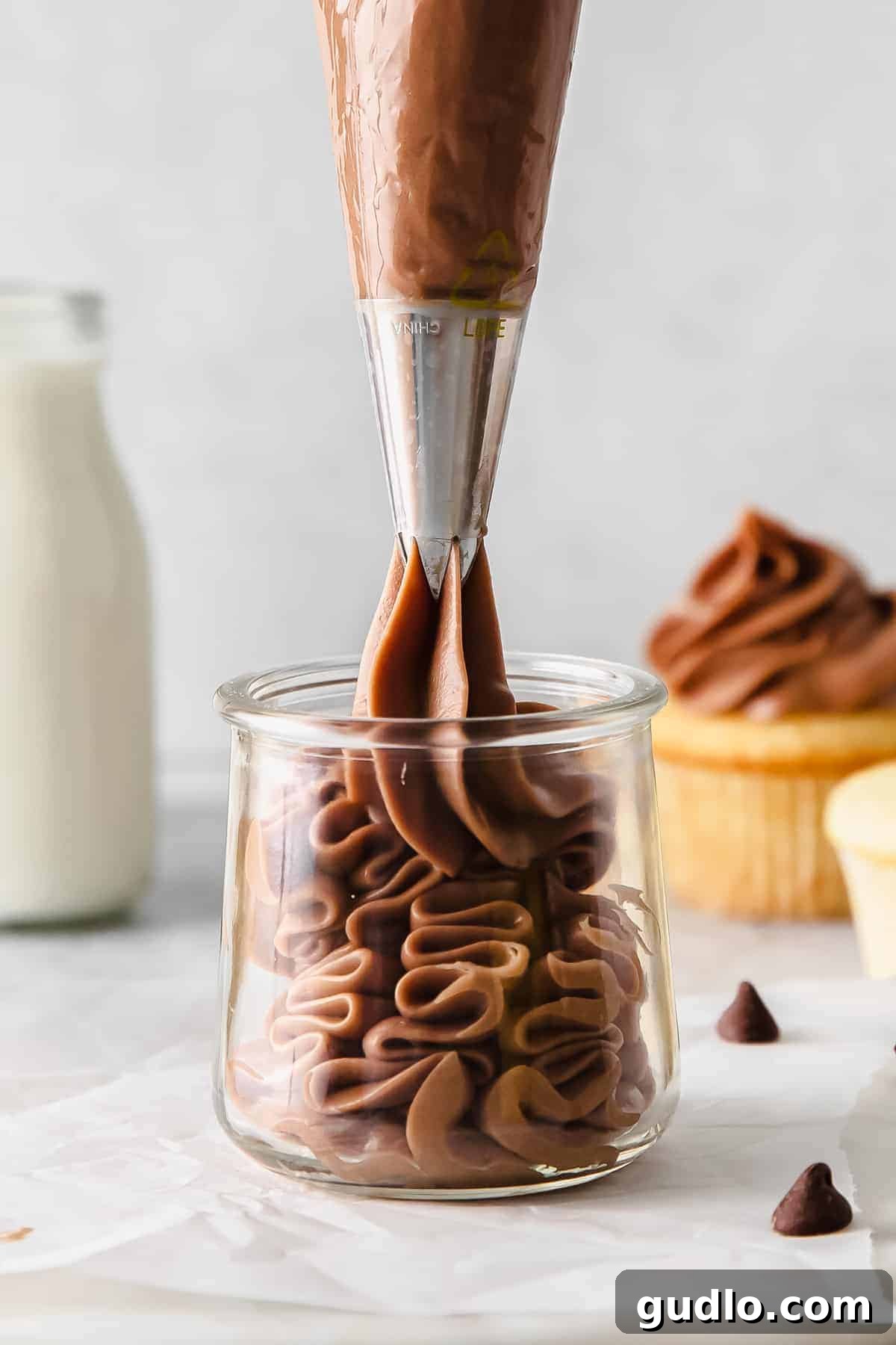 Velvety Chocolate Cream Cheese Delight 6 Chocolate cream cheese frosting being piped into a small glass jar, perfect for gifting or dipping. You can use this chocolate cream cheese frosting as a sweet dip for graham crackers or fruit!