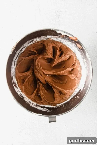 Velvety Chocolate Cream Cheese Delight 9 Rich chocolate cream cheese frosting being whipped to perfection in a stand mixer, demonstrating its fluffy texture.