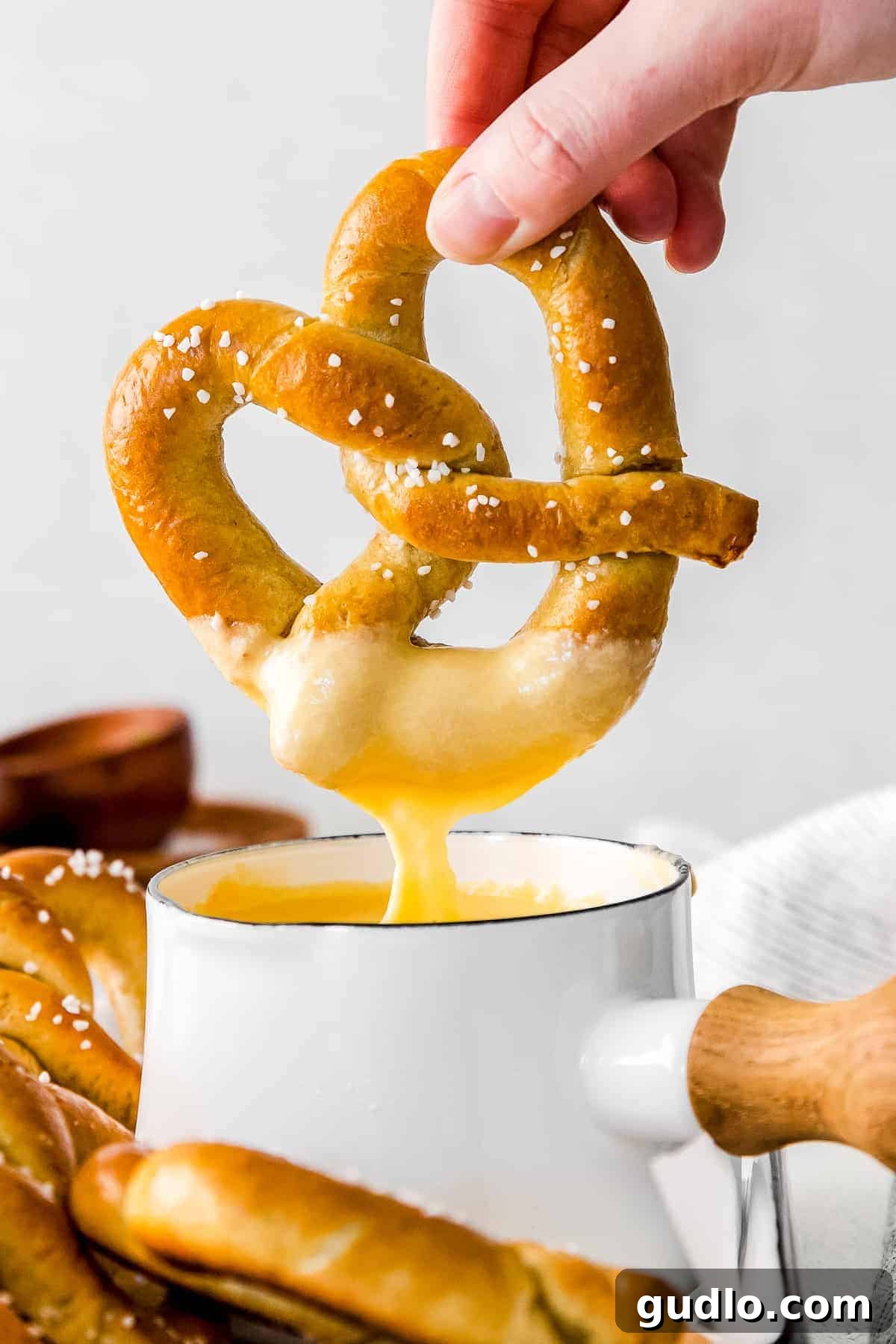 Creamy Beer Cheese Fondue 2 A soft pretzel being dipped into a warm, golden beer cheese dip, showcasing its creamy texture.