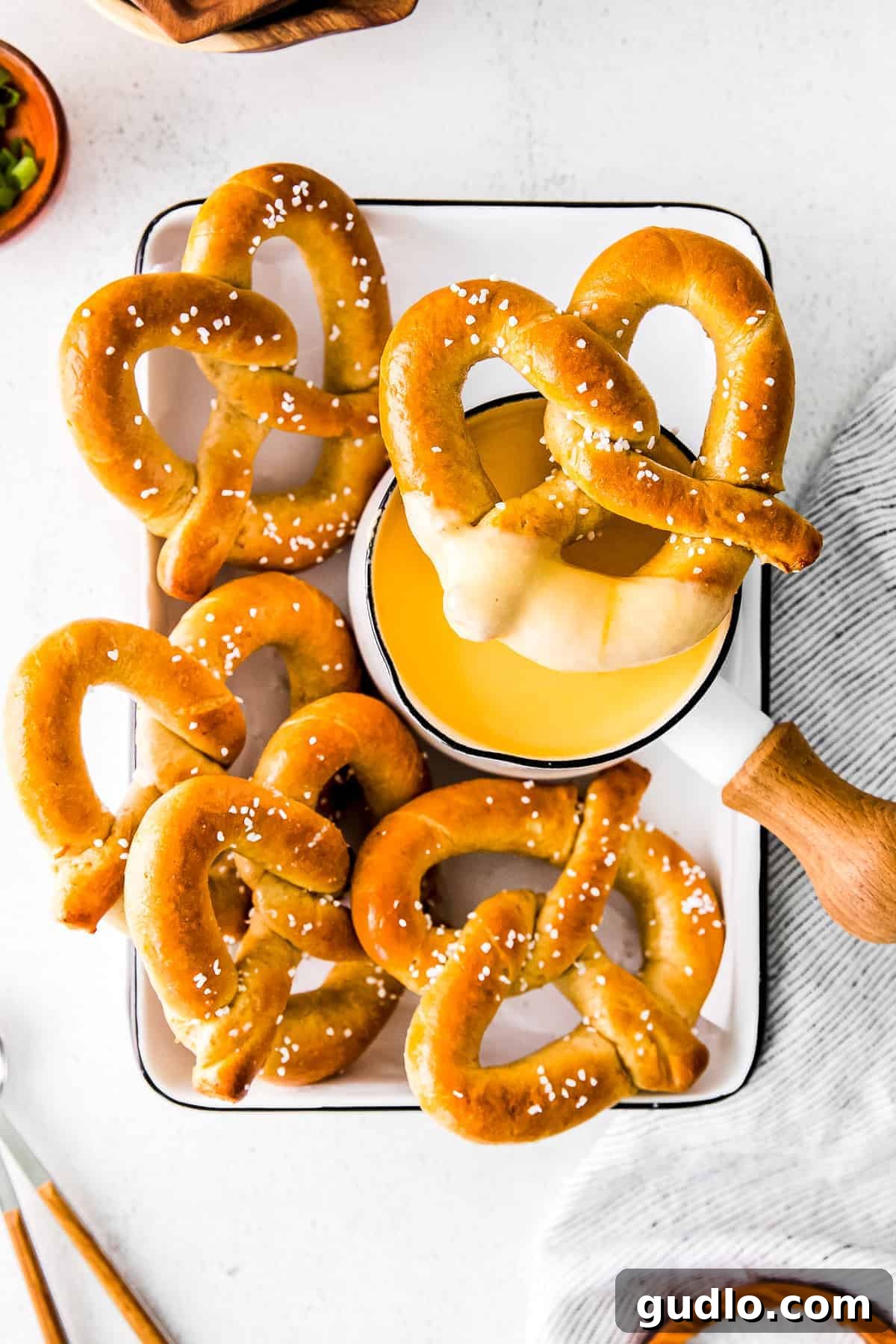 Creamy Beer Cheese Fondue 9 A hand dipping a soft pretzel into a bowl of rich, warm beer cheese dip, highlighting a classic game day pairing.