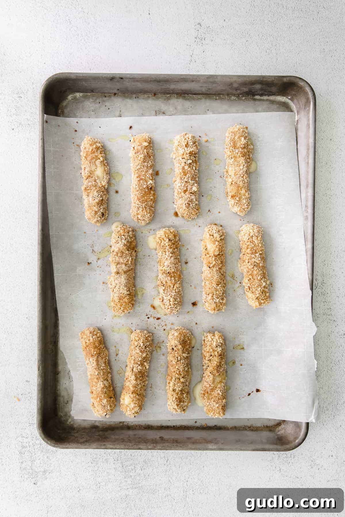 Crispy Homemade Mozzarella Sticks 5 Baked homemade mozzarella sticks resting on a parchment-lined baking tray