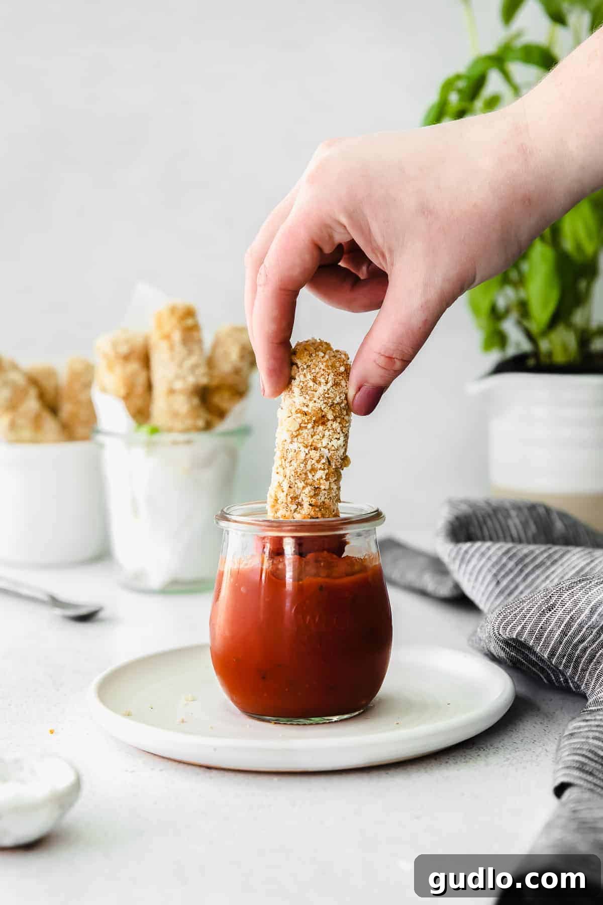 Crispy Homemade Mozzarella Sticks 7 Homemade mozzarella stick being dipped into a bowl of vibrant red marinara sauce