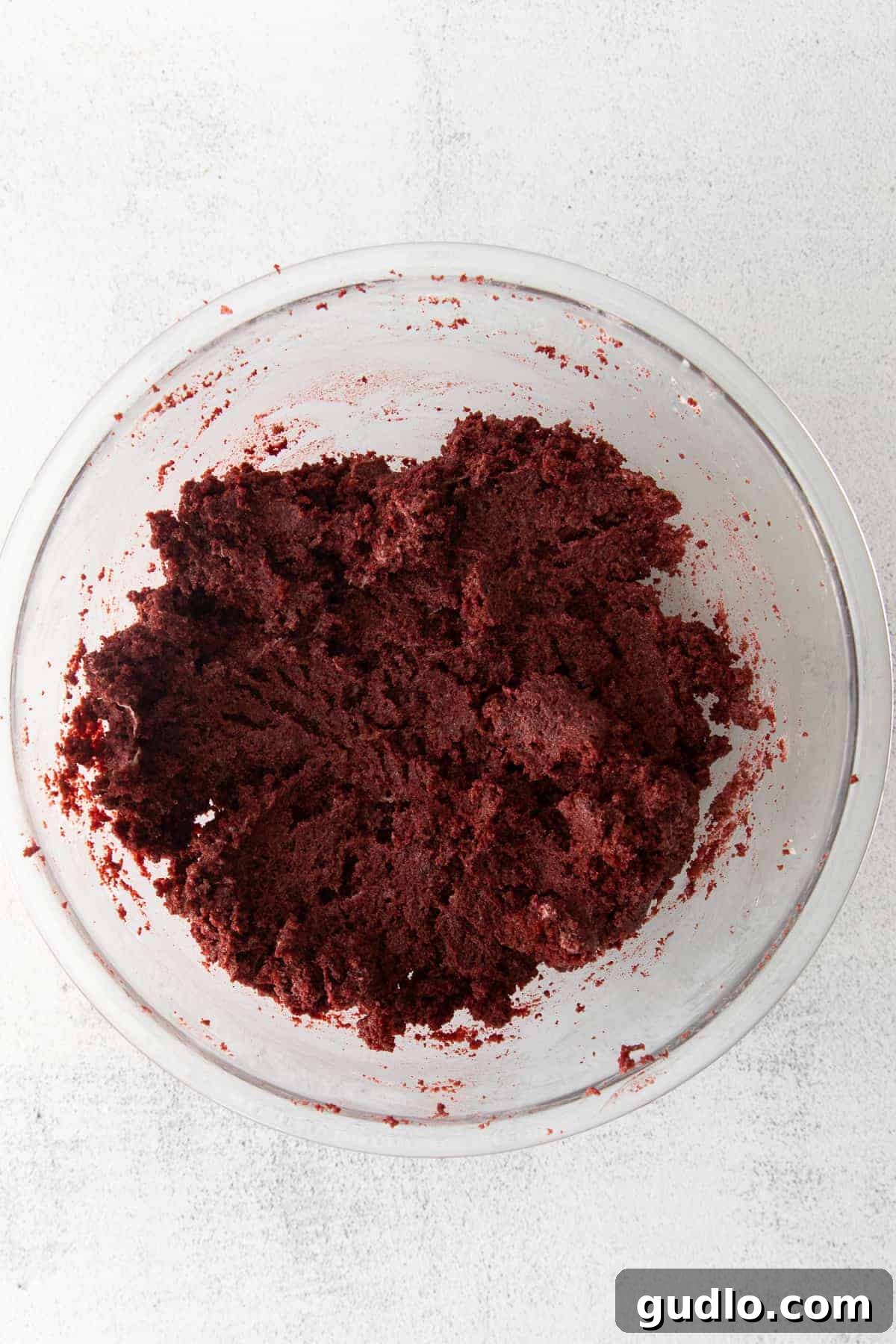 Make these spooky Red Velvet Mummy Truffles for a fun Halloween treat the whole family can help make! The vibrant red velvet truffle mixture, a blend of crumbled cake and cream cheese frosting, in a mixing bowl, ready for shaping.
