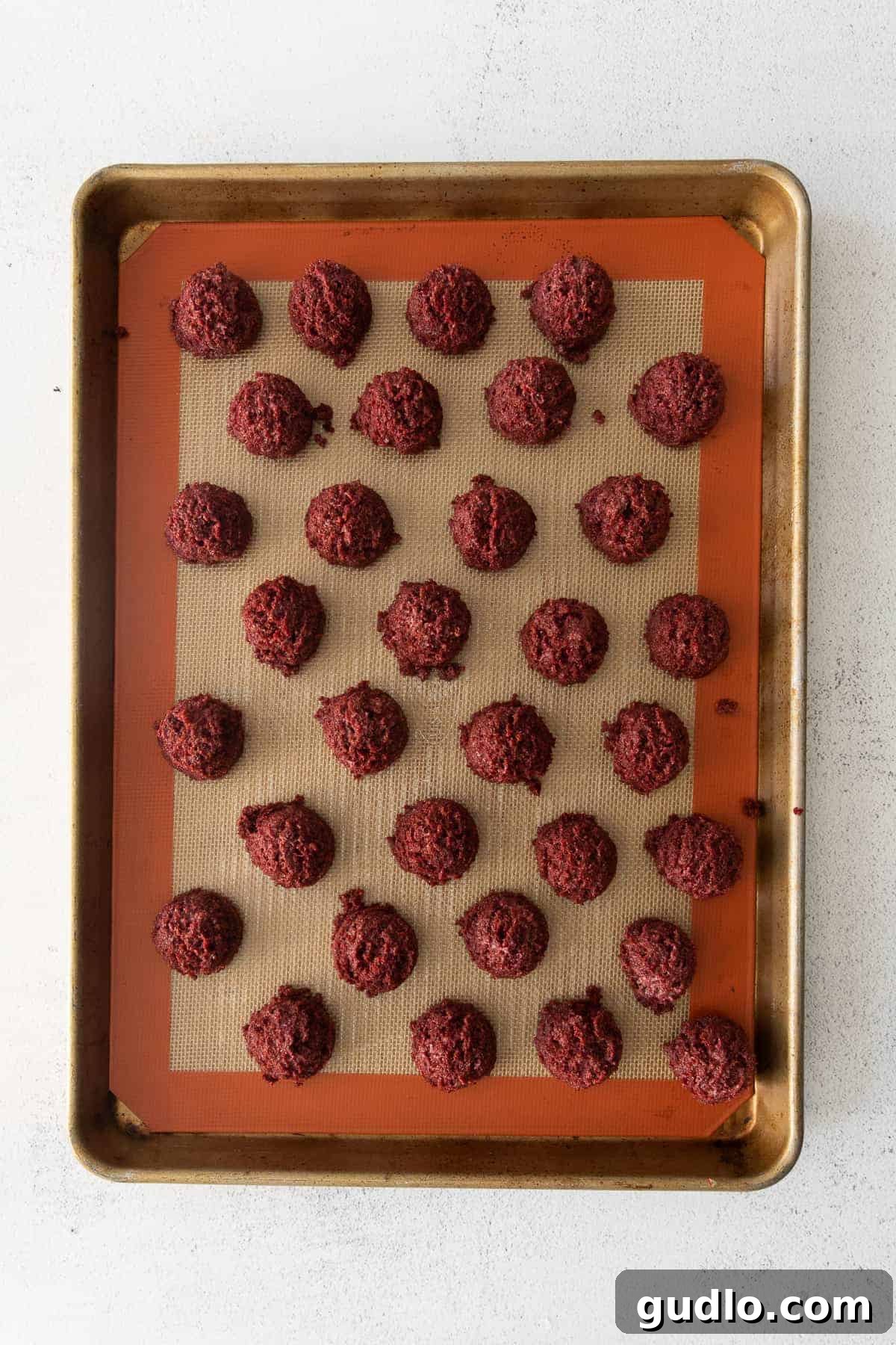 Red Velvet Mummy Truffles: Happy Halloween from these delicious dessert truffles! Perfectly scooped, uniform red velvet truffle balls arranged neatly on a baking sheet lined with parchment paper, ready for chilling.