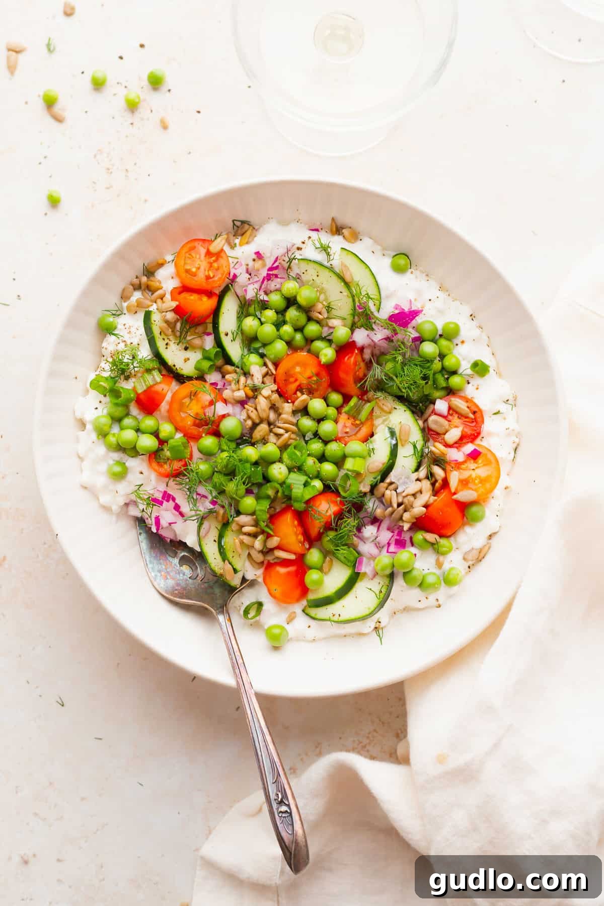 Fresh Cottage Cheese Salad with Sunflower Seeds, Veggies, and Herbs A beautifully presented cottage cheese salad in a white bowl, garnished with sunflower seeds, fresh vegetables, and herbs, ready to be enjoyed.
