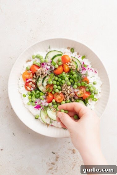 Wholesome Cottage Medley 4 A person assembling a cottage cheese salad with vegetables and peas.