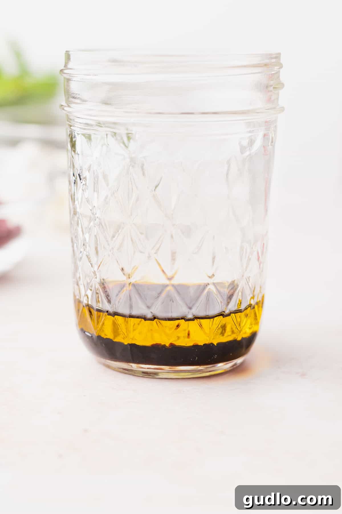 A mason jar filled with homemade balsamic vinaigrette, ready to dress a fresh arugula goat cheese salad, highlighting simplicity and fresh ingredients.
