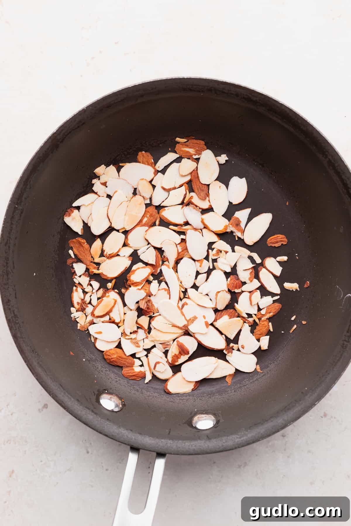 Slivered almonds in a skillet, gently toasting to a golden brown, ready to add a perfect crunch to the salad.