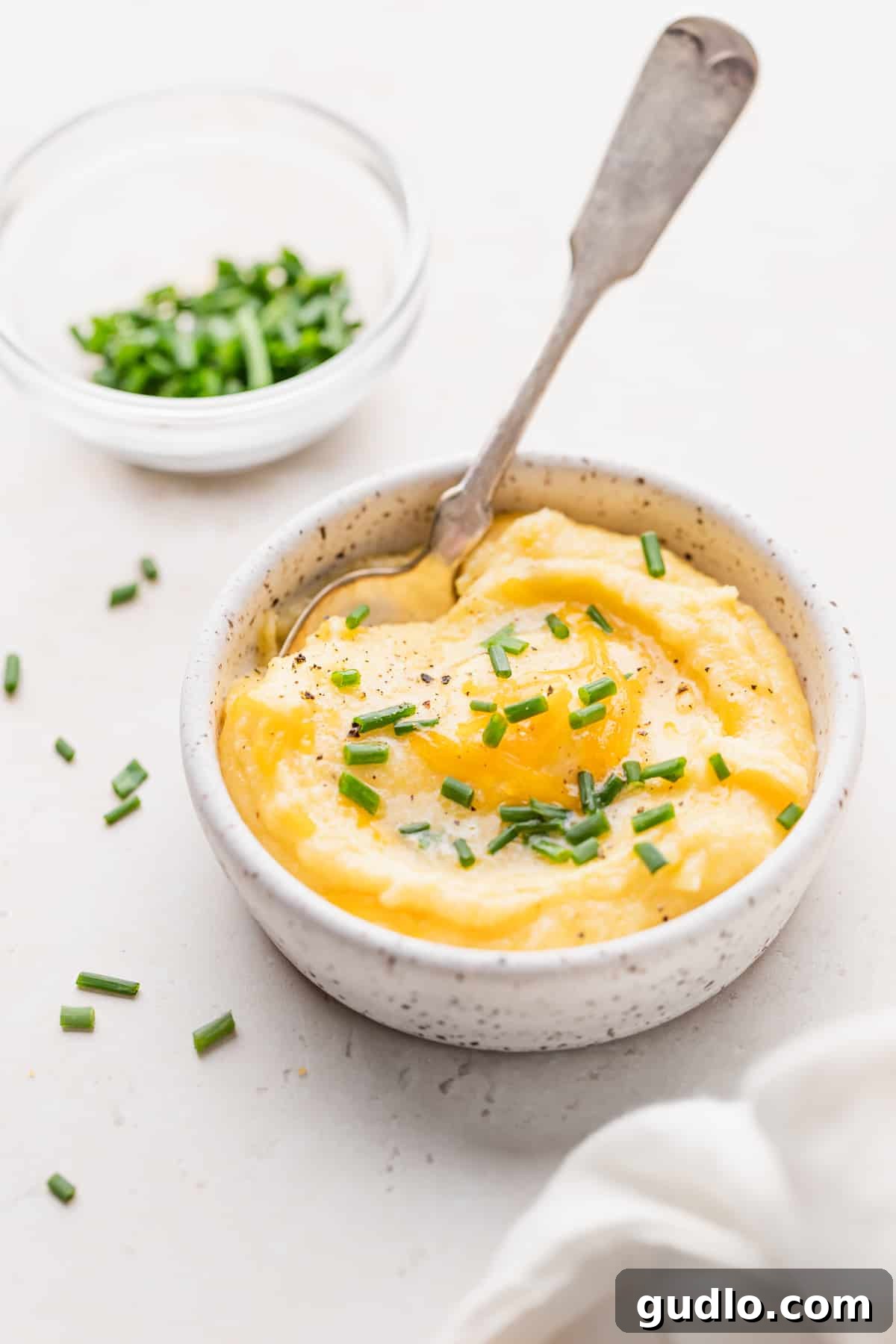 Garnished Cheese Grits: A Perfect Finish A close-up of a bowl of rich, creamy cheese grits, garnished with vibrant fresh chives, ready to be devoured.