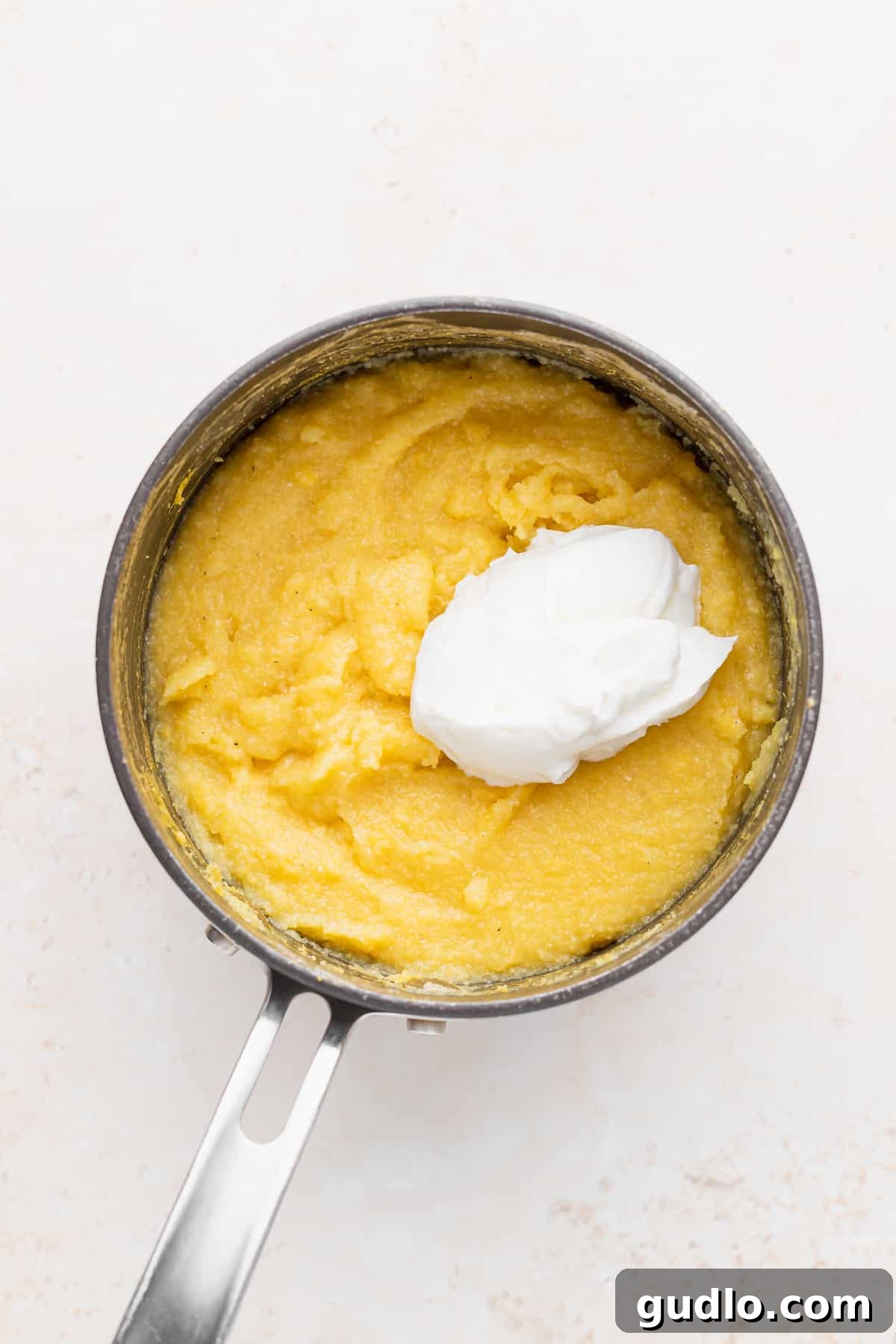 Incorporating Greek Yogurt for Creamy Grits Creamy Greek yogurt being stirred into perfectly cooked cornmeal, creating the foundation for truly luscious cheese grits.