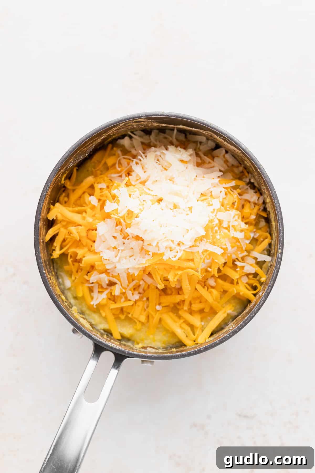 The Heart of Flavor: Parmesan and Cheddar in Grits A glorious pot filled with creamy grits, generously studded with shredded Parmesan and vibrant yellow cheddar cheese, ready for a final stir.
