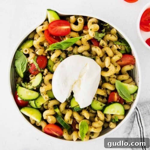 A delicious pesto pasta salad with burrata, vibrant and inviting, presented in a round serving dish.